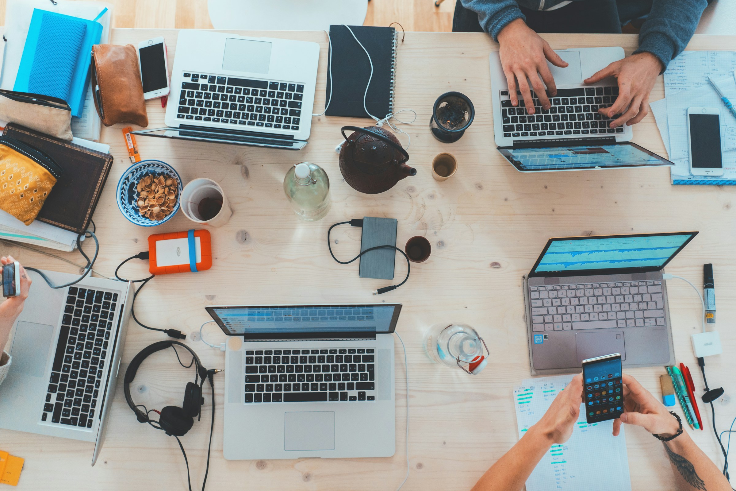 Designers collaborating on laptops around a table.