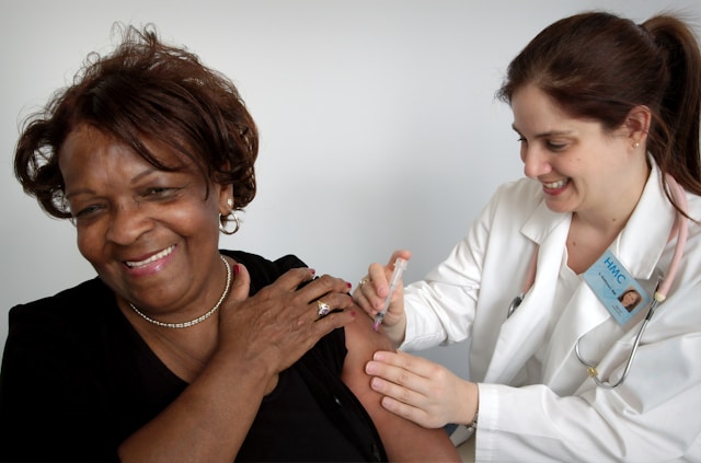 Woman receiving a vaccination by a GP.